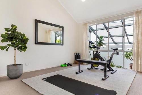 a room with a gym with a treadmill and a mirror at Amazing Canal House with Private Jetty, Gym & Pool in Mooloolaba