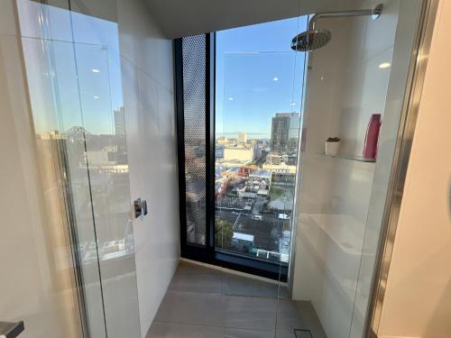 La salle de bains est pourvue d'une douche en verre et offre une vue sur la ville. dans l'établissement Luxury 1-Bed with Infinity Pool, Gym & Parking, à Brisbane