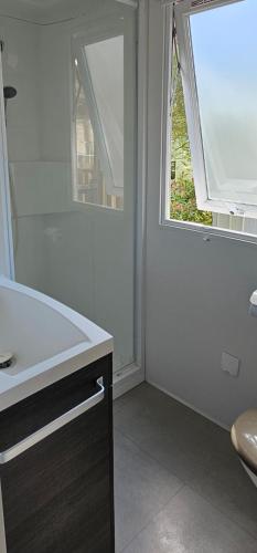 a white bathroom with a sink and a window at Mobil home La palmyre 8 Pers in Les Mathes
