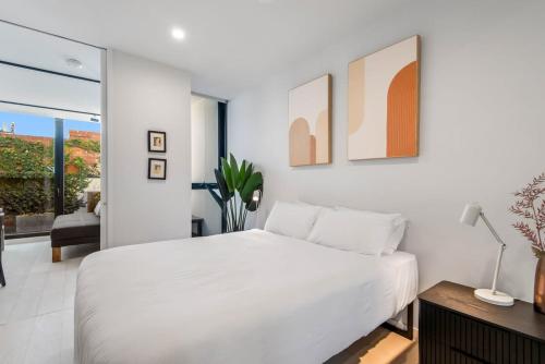 a white bedroom with a large bed and a table at MadeComfy Inner City Designer 2-Bed Apartment in Melbourne