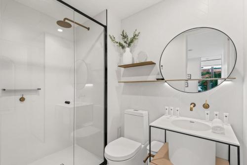een badkamer met een toilet, een wastafel en een spiegel bij MadeComfy Inner City Designer 2-Bed Apartment in Melbourne