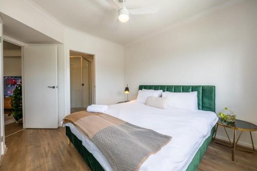 a bedroom with a large white bed with a green headboard at Tranquil 2-Bed Inner City Retreat with Parking in Brisbane