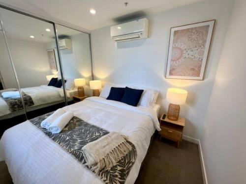 una camera da letto con un grande letto bianco e uno specchio di 2-Bed with Pool, Gym, Parking and Balcony a Brisbane