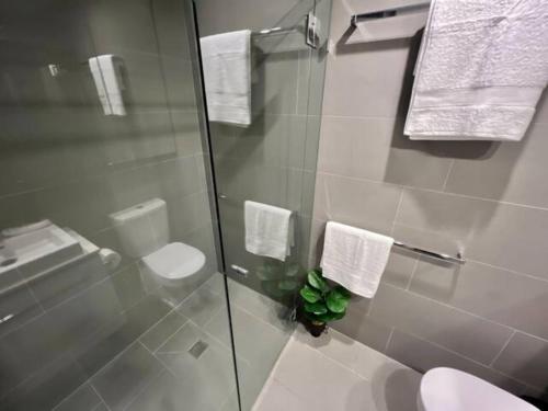 a bathroom with a toilet and a glass shower at 2-Bed with Pool, Gym, Parking and Balcony in Brisbane
