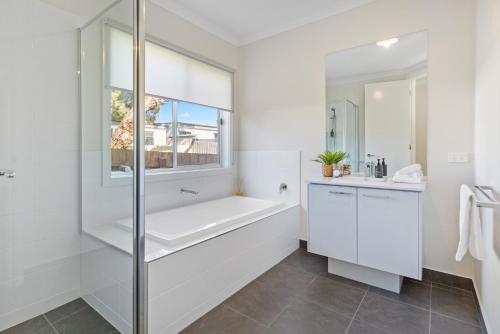 Un baño blanco con bañera y ventana. en Seaslife - Stylish Family Rosebud Accommodation, en Rosebud