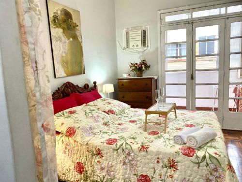1 dormitorio con 1 cama con colcha de flores en Apartamento Teresópolis - Centro en Teresópolis