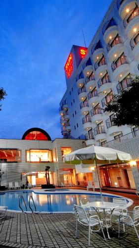 a hotel building with chairs and a pool in front of it at Resorpia Kumihama in Kyotango
