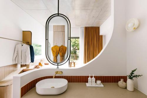 ein Bad mit einem runden Spiegel und einem Waschbecken in der Unterkunft Basq House in Byron Bay