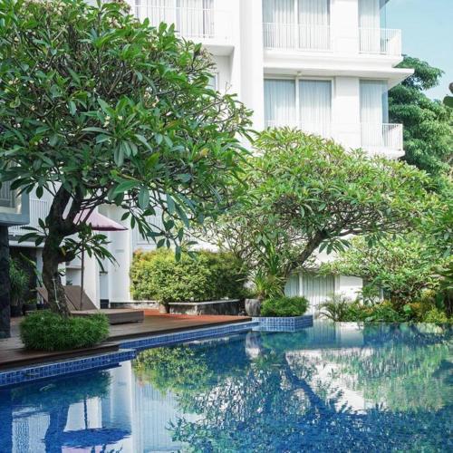 a swimming pool with trees in front of a building at Teras Sinabung in Candi