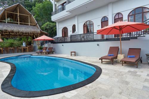 a pool with chairs and umbrellas next to a building at Attara Hills Sunset Villa Senggigi in Senggigi 
