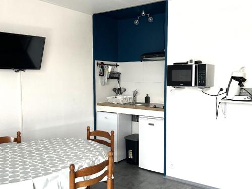 une petite cuisine avec une table et un micro-ondes dans l'établissement Appartement en Front de Mer avec Parking Privatif à St Jean de Monts - Accès Direct Plage & Pistes Cyclables - FR-1-652-42, à Saint-Jean-de-Monts