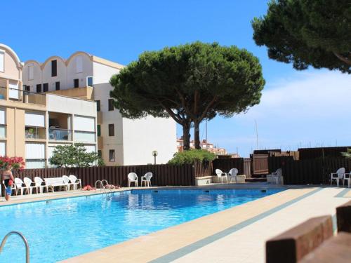 - une piscine avec des chaises et un arbre dans l'établissement Appartement 6 couchages avec piscine à Gruissan - FR-1-229-888, à Gruissan