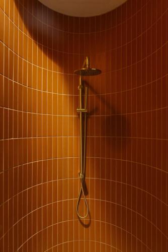 a shower in a bathroom with orange tiles at Basq House in Byron Bay