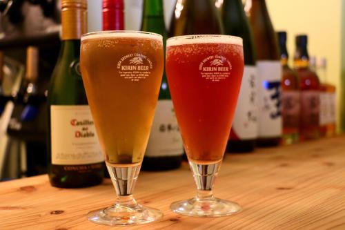 two glasses of beer sitting on a table with wine bottles at 料理旅館ゆり野 in Wajiki