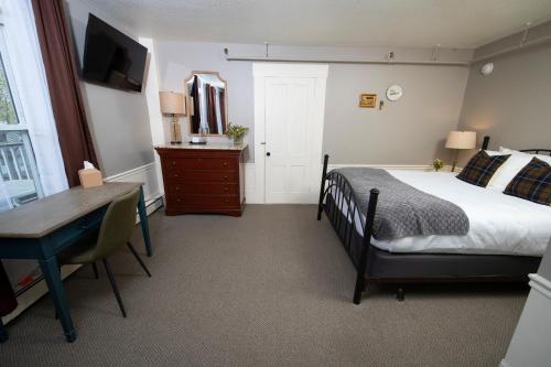 a bedroom with a bed and a desk and a table at The New London Inn in New London