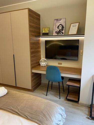 a bedroom with a desk with a television and a blue chair at Republica del Salvador Coliving Ecuador XOE in Quito