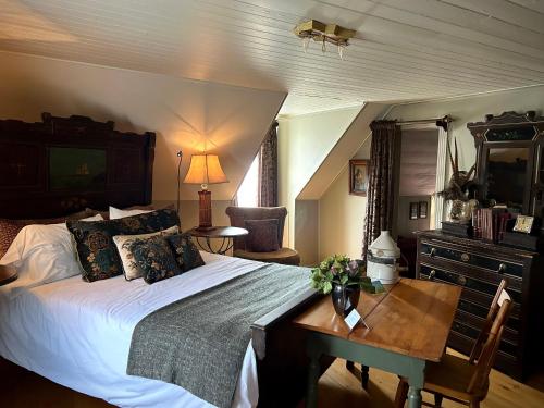 Schlafzimmer mit einem Bett, einem Tisch und einem Schreibtisch in der Unterkunft Le Mange Grenouille in Bic