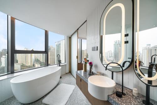 A T HOUSE Shanghai Xujiahui في شانغهاي: حمام مع حوض أبيض كبير ومغسلة