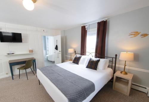 a bedroom with a large bed and a desk at The New London Inn in New London
