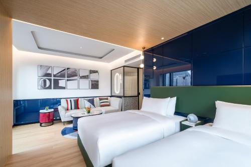 a hotel room with two beds and a couch at A T HOUSE Shanghai City Center Xujiahui - Free Night Snacks from 930pm-11pm in Shanghai