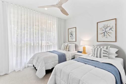 une chambre avec deux lits et un ventilateur de plafond dans l'établissement Haven On Hooper, à Gold Coast