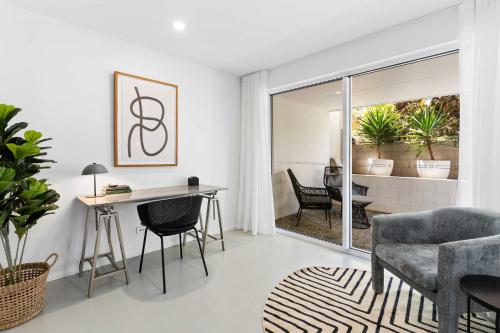 a white living room with a table and chairs at Haven On Hooper in Gold Coast