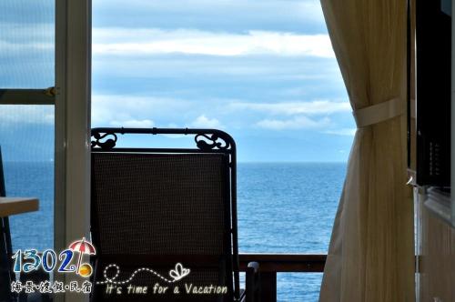 a chair sitting on a balcony looking out at the ocean at 1302海景民宿 in Xiaoliuqiu