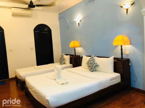 2 camas en una habitación con 2 lámparas en la pared en Pride Resort Cambodia en Phnom Penh