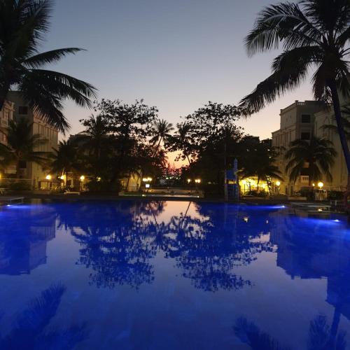 a large swimming pool with palm trees at night at Green Inn Phu Quoc Hotel in Phu Quoc