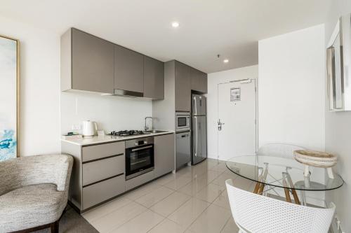 a kitchen with stainless steel appliances and a glass table at Rhapsody Resort - Official in Gold Coast