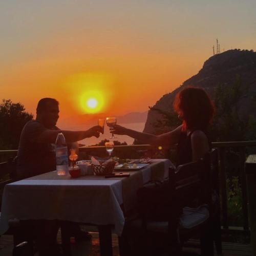 a man and woman sitting at a table with wine glasses at Montenegro Motel in Faralya