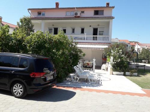 a black minivan parked in front of a house at Apartment Daisy- excellent location close to Rab in Rab
