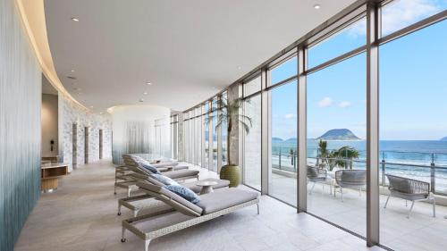 a room with chairs and windows and the ocean at Karatsu Seaside Hotel in Karatsu