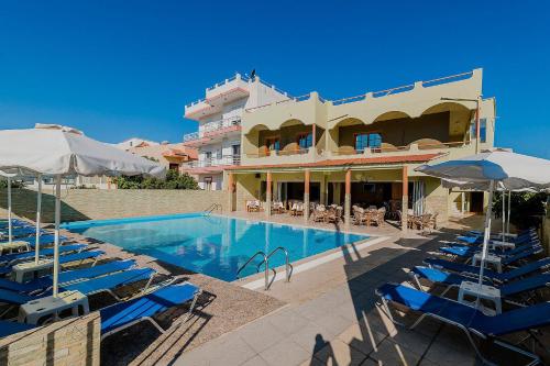 a hotel with a swimming pool with chairs and umbrellas at Esmeralda Hotel in Kremasti