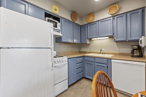 eine Küche mit blauen Schränken und einem weißen Kühlschrank in der Unterkunft SNOW FLOWER 072 condo in Park City