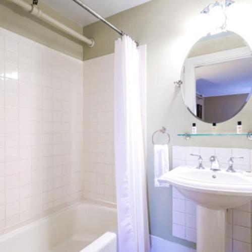 a bathroom with a sink and a tub and a mirror at The New London Inn in New London