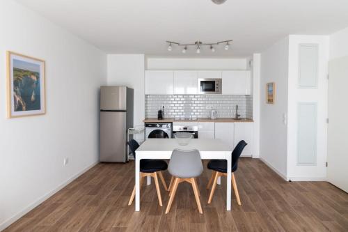 une cuisine blanche avec une table et des chaises blanches dans l'établissement Appartement Mer Parking Balcon 4Pers, à Vendays-Montalivet