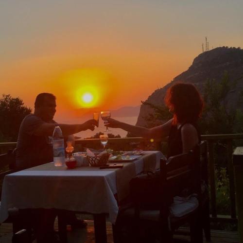 a man and woman sitting at a table with wine glasses at Montenegro Motel in Faralya