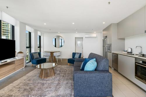 a living room with a couch and a table and a kitchen at Rhapsody Resort - Official in Gold Coast