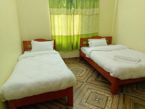 two beds in a small room with a window at Mangal homestay in Pokhara