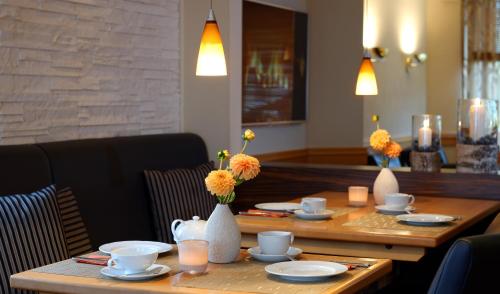 a wooden table with flowers in vases on it at Trend Hotel in Oldenburg
