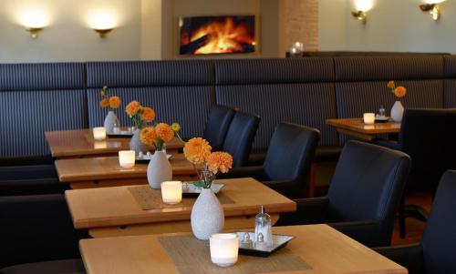 a restaurant with tables and vases with flowers on them at Trend Hotel in Oldenburg