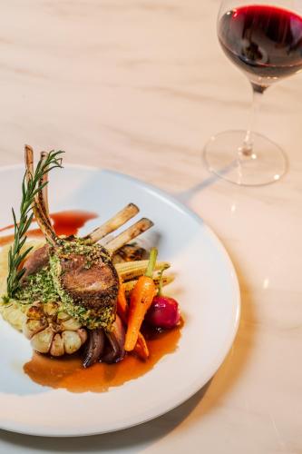 a plate of food with meat and vegetables and a glass of wine at The Five Residences Hanoi in Hanoi
