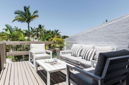 a patio with a couch and chairs on a wooden deck at Sunset Sound Noosa in Noosa Heads