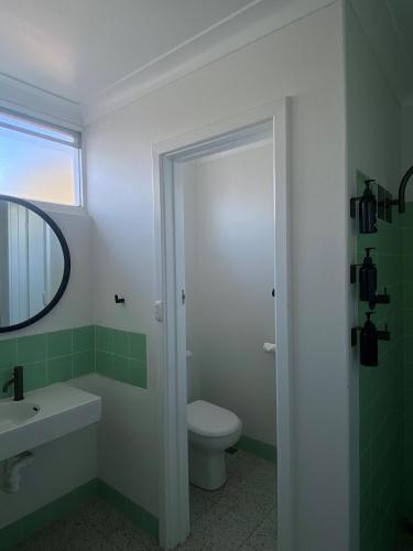 a bathroom with a toilet and a sink and a mirror at Paradise Motel Busselton in Busselton