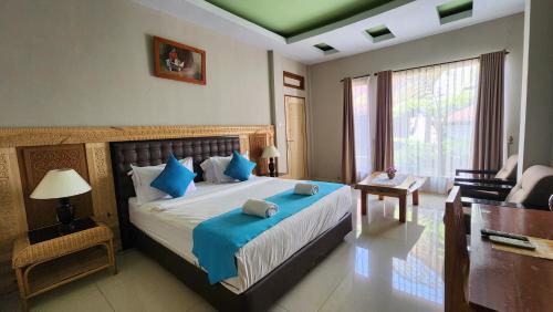 a bedroom with a large bed with blue pillows at Toraja Banua Hotel in Rantepao