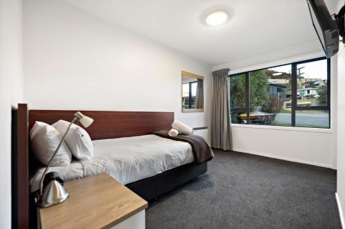 a bedroom with a bed and a large window at Town centre house. Perfect for families and groups in Queenstown