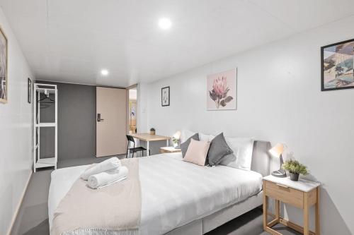 una camera da letto bianca con un letto grande e un tavolo di Detached Queen Room in Pymble - Serene Spot - Shared Bathroom a Pymble