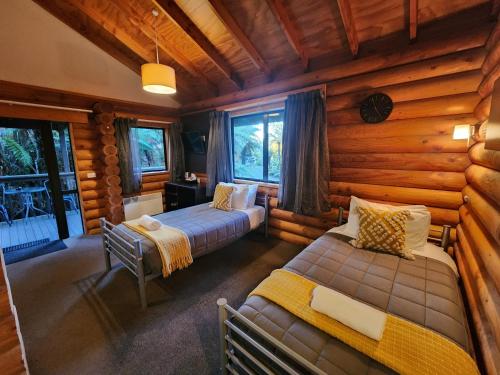 um quarto com 2 camas num chalé de madeira em Rainforest Retreat em Franz Josef