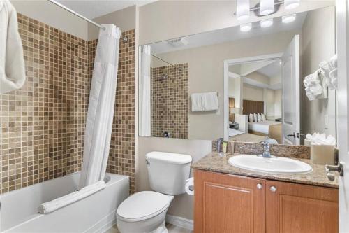 a bathroom with a toilet and a sink and a mirror at Premier Resort Condos Near Disney & Universal in Orlando